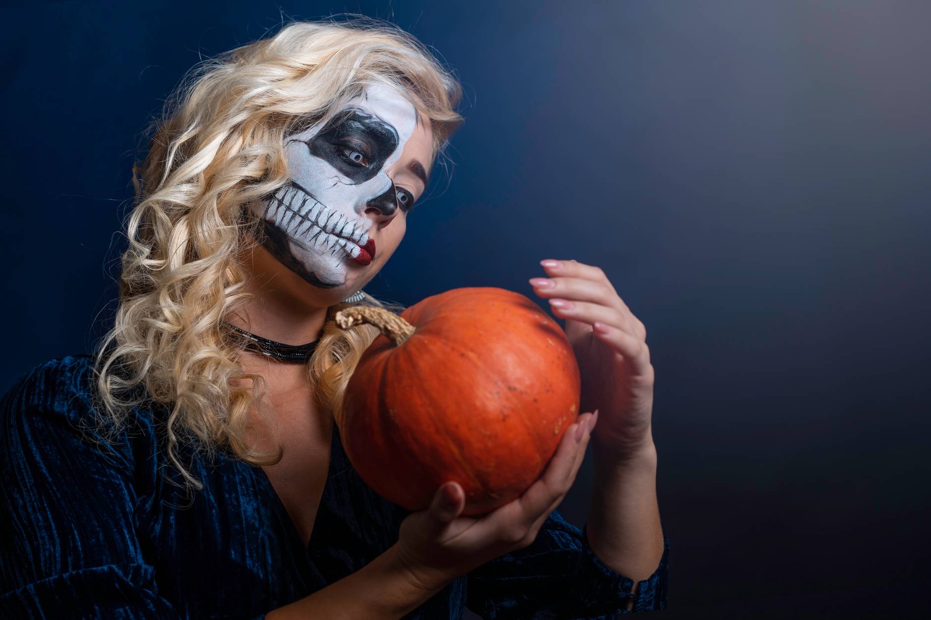 woman with face paint with pumpkin